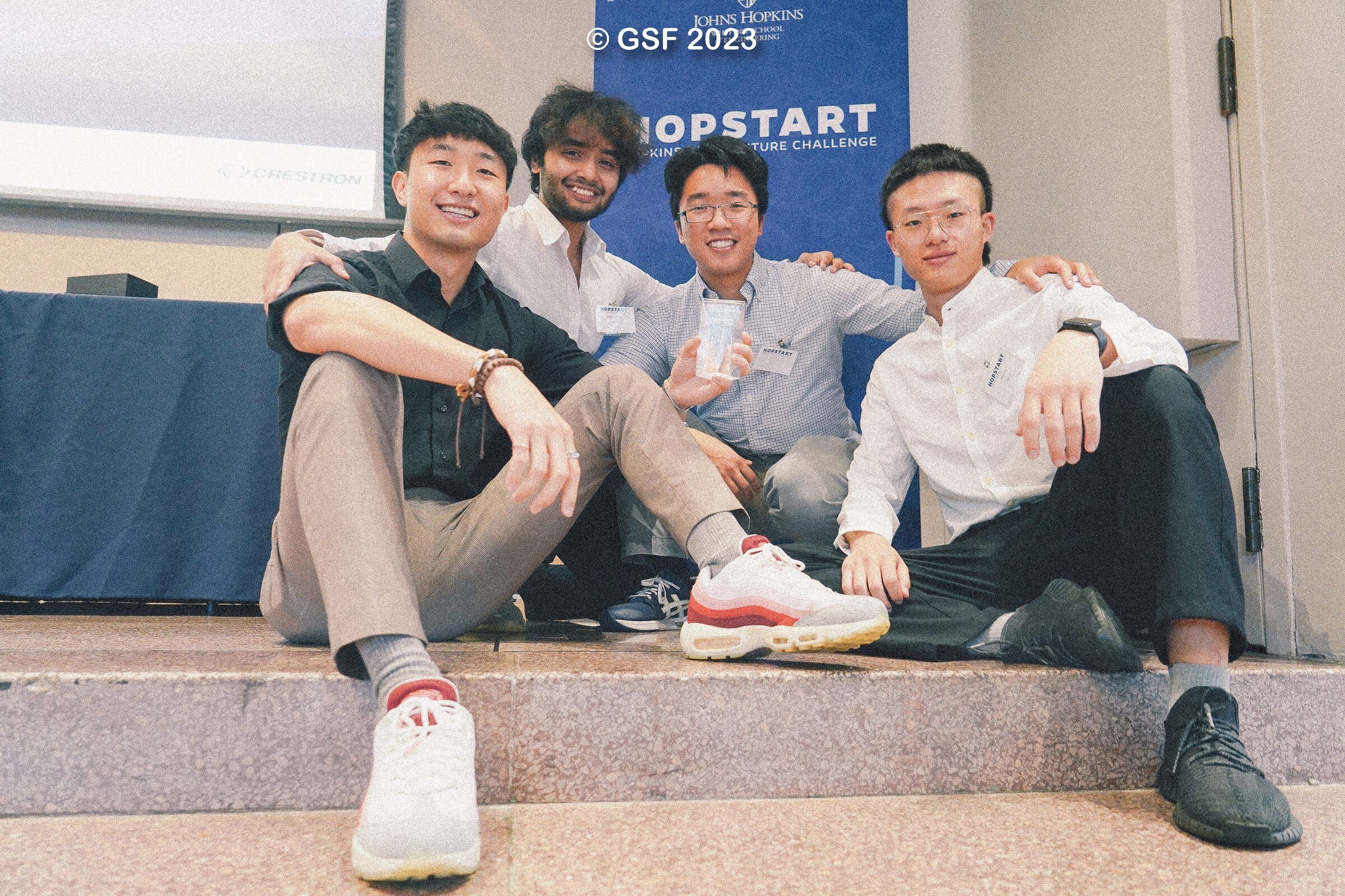 The EdDen team sitting together on a step after winning Hopstart, holding the trophy.