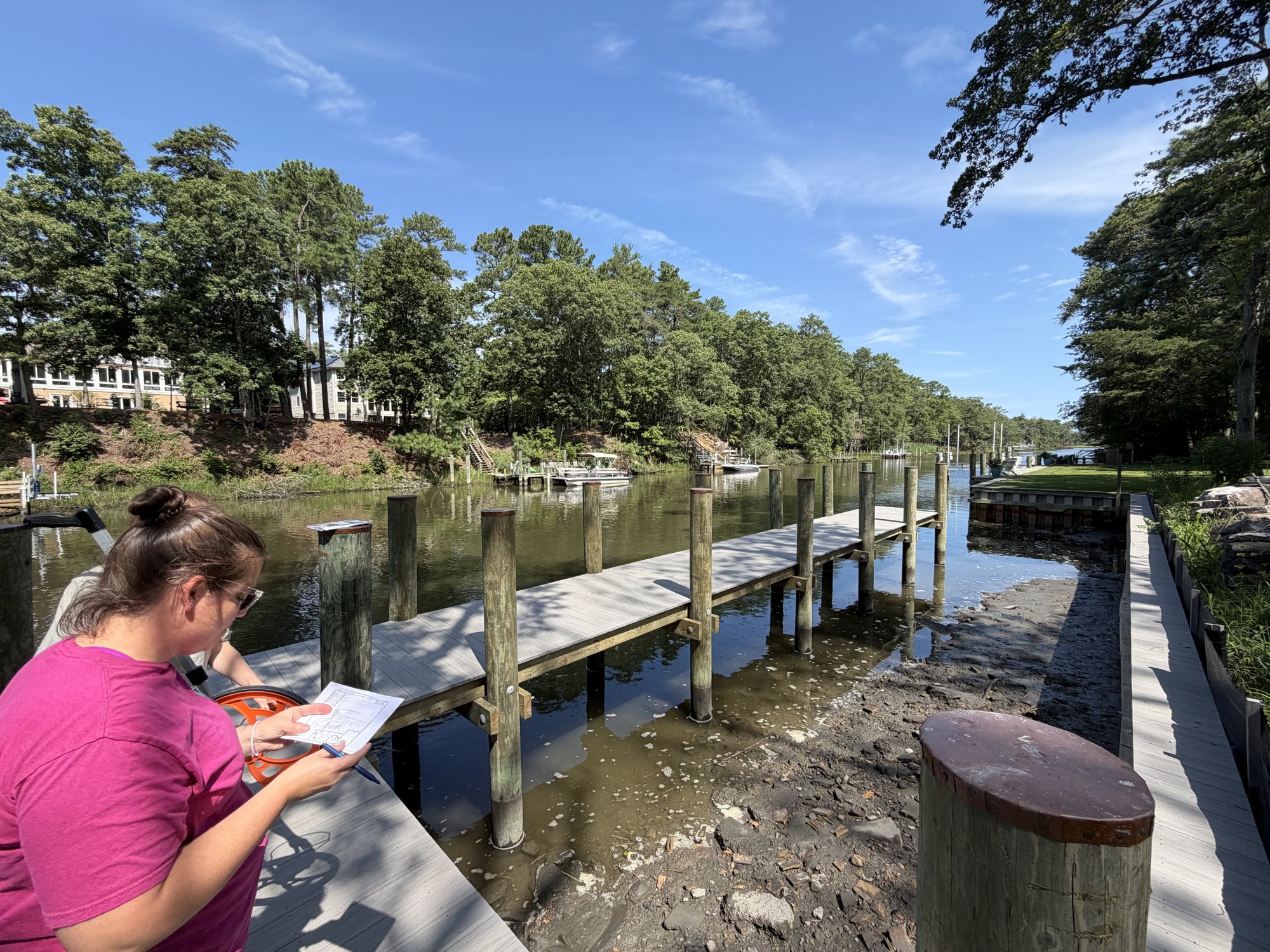 A scientist on a dock checking a site plan during a field inspection.