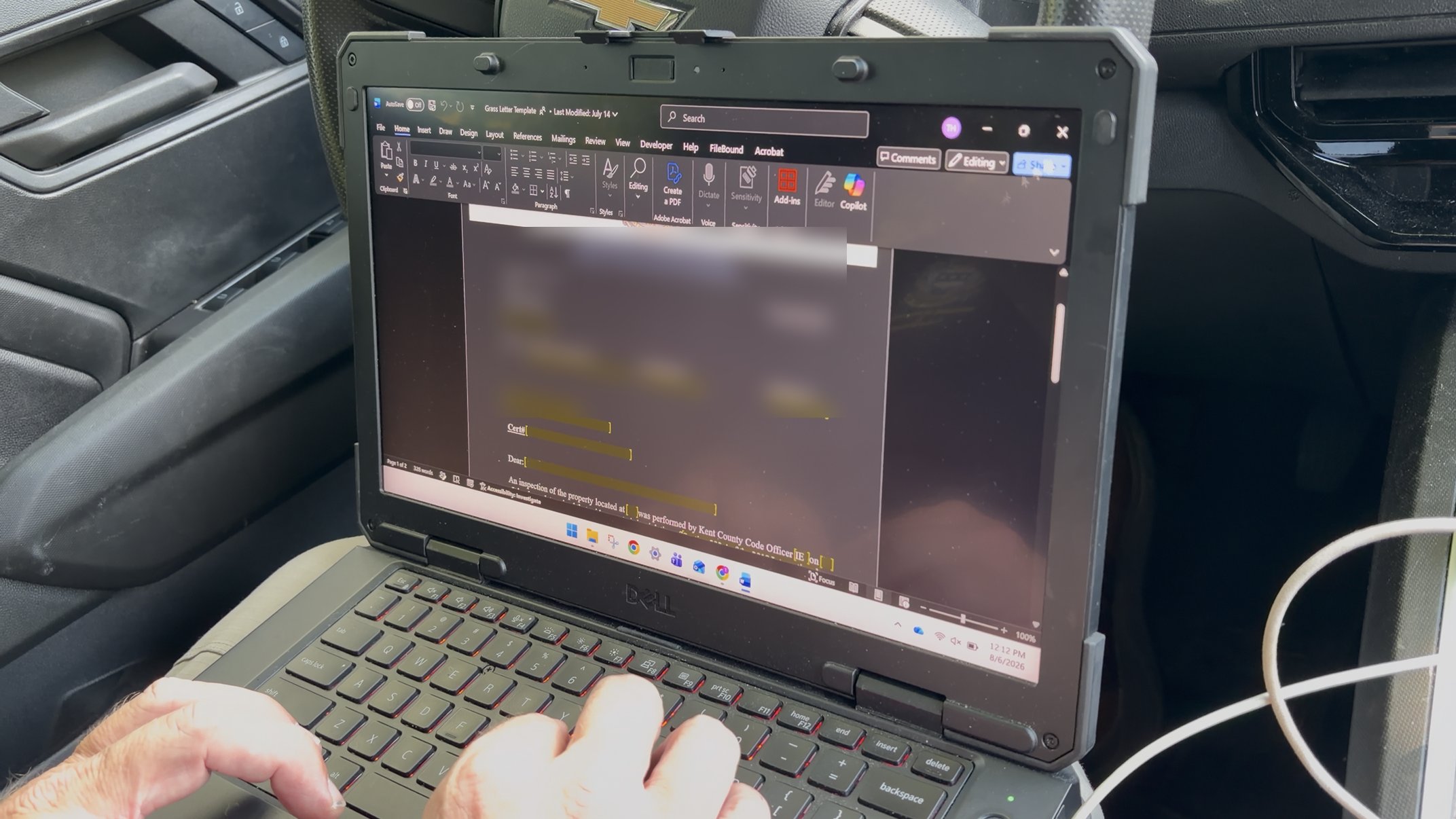 A rugged in-truck laptop showing a Word violation-letter template that an inspector fills in by hand.
